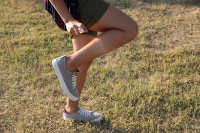Photo of Woman applying insect repellent onto leg outdoors, closeup. Space for text