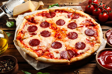 Photo of Hot delicious pepperoni pizza on wooden table