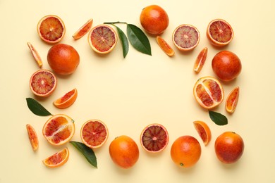 Frame of ripe sicilian oranges and leaves on beige background, flat lay. Space for text