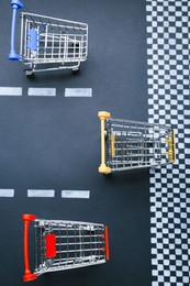 Competition concept. Shopping carts racing towards finish line, flat lay