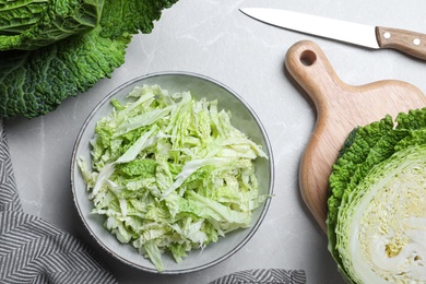 Photo of Cut fresh savoy cabbage on light marble table, flat lay