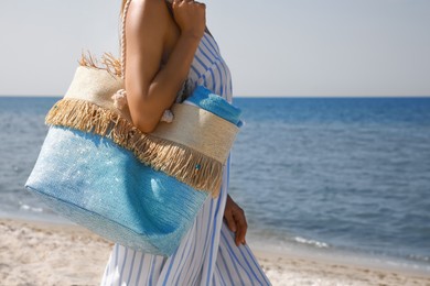 Woman with beach bag near sea on sunny day, closeup. Space for text