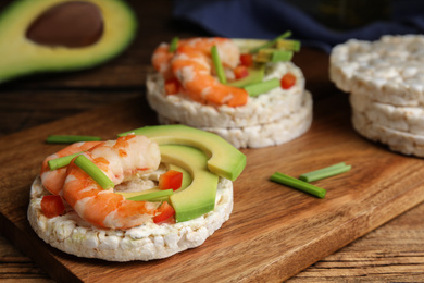 Puffed rice cakes with shrimps and avocado on wooden board, closeup