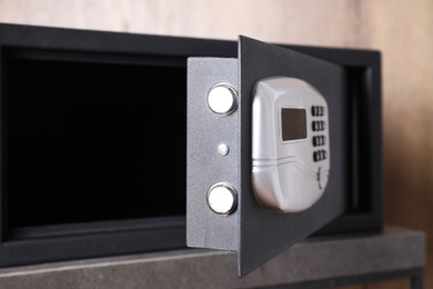 Black steel safe with electronic lock on grey table, closeup