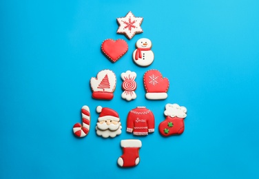 Delicious gingerbread cookies arranged in shape of Christmas tree on light blue background, flat lay