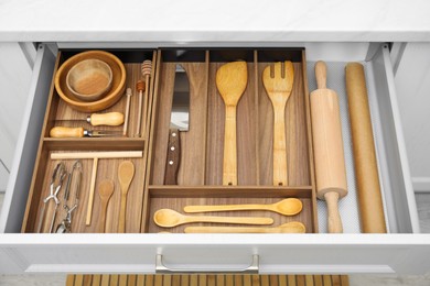 Photo of Open drawer of kitchen cabinet with different utensils, above view