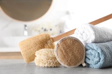 Photo of Natural loofah sponges and towels on table in bathroom