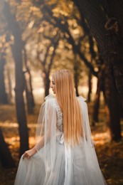 Beautiful girl wearing fairy dress in autumn forest, back view