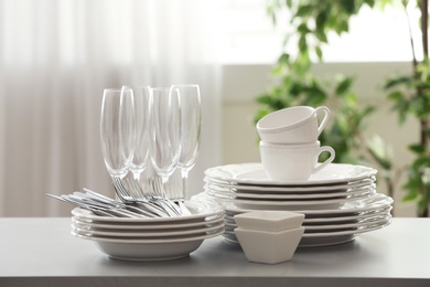 Photo of Set of clean dishware, cutlery and champagne glasses on table indoors
