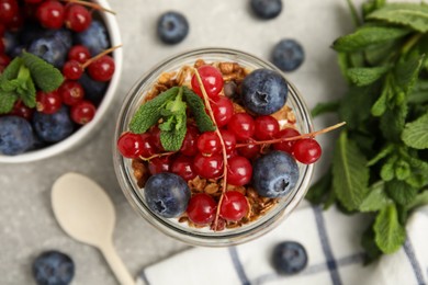 Delicious yogurt parfait with fresh berries and mint on light grey table, flat lay