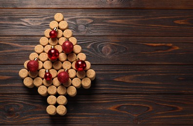 Photo of Christmas tree made of wine corks and red baubles on wooden table, top view. Space for text