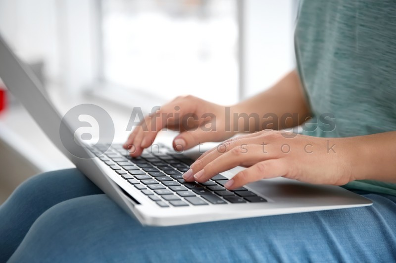 Young woman using laptop indoors, closeup