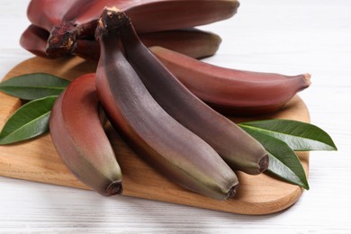 Tasty red baby bananas on white table, closeup