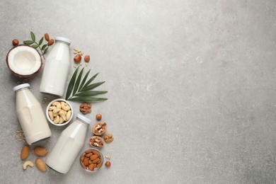 Vegan milk and different nuts on grey table, flat lay. Space for text