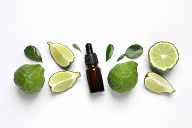 Glass bottle of bergamot essential oil and fresh fruits on white background, flat lay