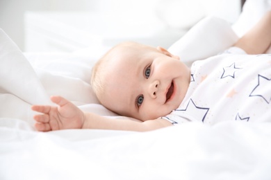 Cute smiling little baby lying on bed