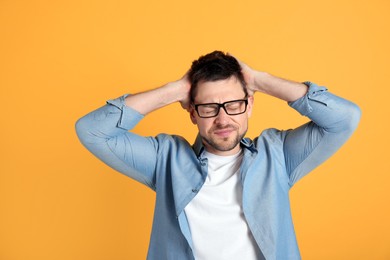 Man suffering from terrible migraine on yellow background