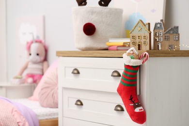 Stocking with presents hanging on drawer in children's room. Saint Nicholas Day tradition