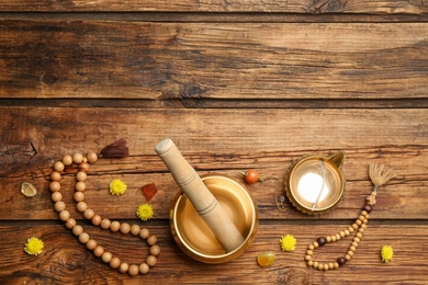 Flat lay composition with golden singing bowl on wooden table, space for text. Sound healing