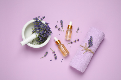 Flat lay composition with lavender flowers and natural essential oil on pink background