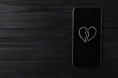 Smartphone with picture of broken heart and space for text on black wooden background, top view. Relationship problems concept