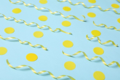 Shiny yellow serpentine streamers and confetti on light blue background