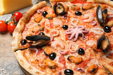 Tasty fresh pizza with seafood on table, closeup
