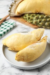 Plate with fresh ripe durian on white marble table