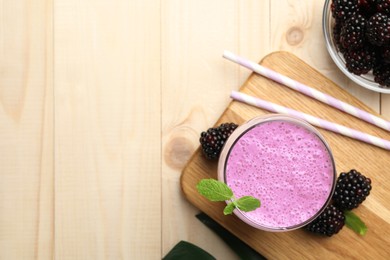 Delicious blackberry smoothie in glass and berries on wooden table, flat lay. Space for text