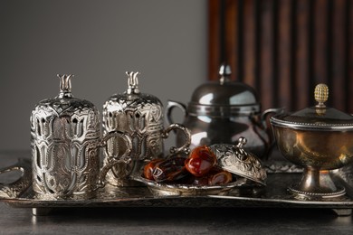 Photo of Tea and date fruits served in vintage tea set on grey textured table