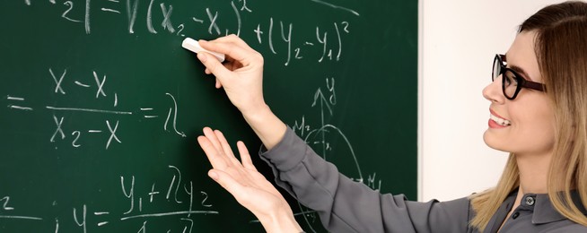 Happy teacher writing on chalkboard in classroom. Banner design