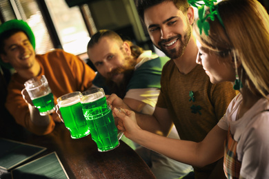 Group of friends toasting with green beer in pub. St. Patrick's Day celebration