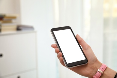 Woman holding smartphone with blank screen indoors, closeup of hand. Space for text