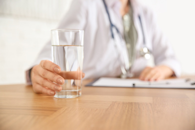 Nutritionist with glass of water at desk in office, closeup