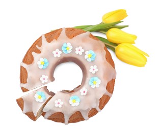Photo of Festively decorated Easter cake and yellow tulips on white background, top view