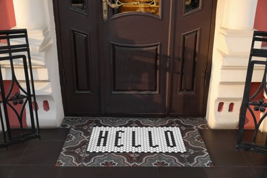 Stylish door mat with word HELLO near entrance