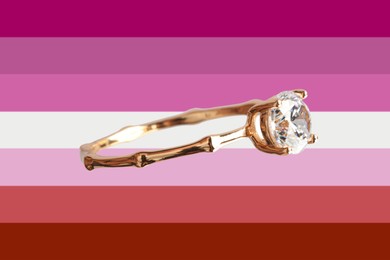 Beautiful engagement ring on background in color of lesbian flag