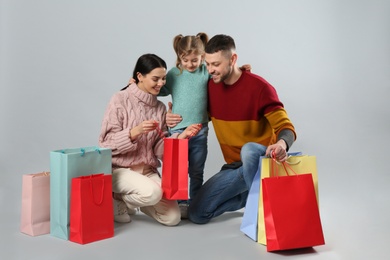 Happy family with paper bags on grey background. Christmas shopping