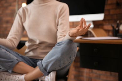Woman meditating at workplace in office, closeup