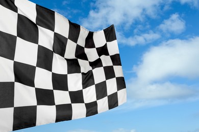 Checkered racing finish flag against blue sky