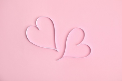 Hearts made of white ribbon on pink background, flat lay. Valentine's day celebration