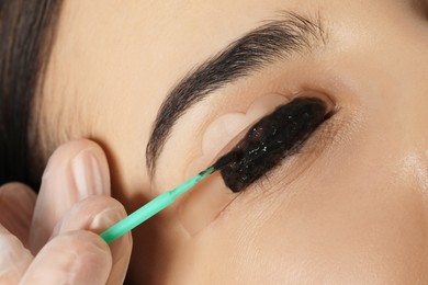 Photo of Young woman undergoing eyelash lamination and tinting, closeup