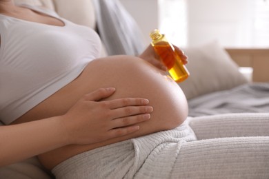 Young pregnant woman with cosmetic product indoors, closeup