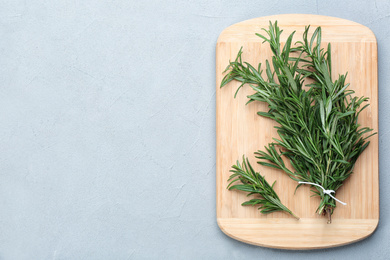 Bunch of fresh rosemary on light grey table, top view. Space for text