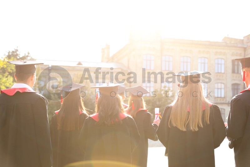 Group of students wearing academic caps and gowns outdoors. Graduation ceremony