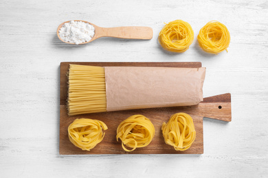 Flat lay composition with different types of pasta on white wooden table