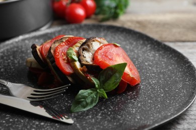 Photo of Delicious ratatouille served with basil on wooden table, closeup