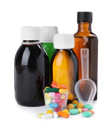 Bottles of syrups, measuring cup, plastic spoon with pills on white background. Cough and cold medicine