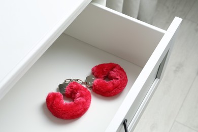 Fluffy handcuffs in open white drawer. Sex toys