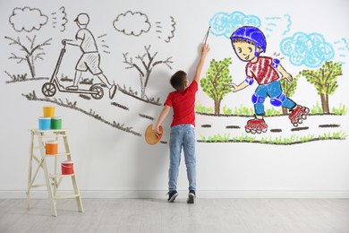 Little boy drawing his dreams on wall, back view